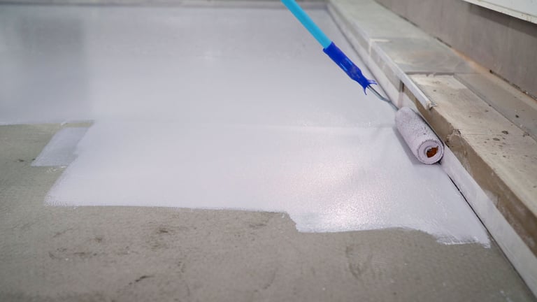 Worker painting floor white using roller