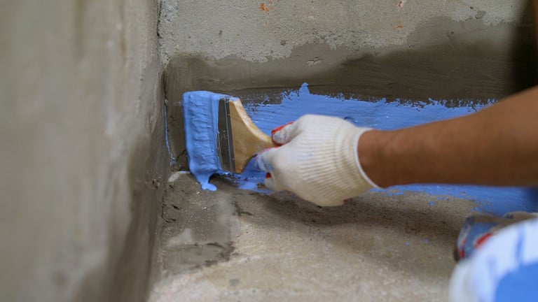 Construction worker applying waterproofing paint on concrete surface