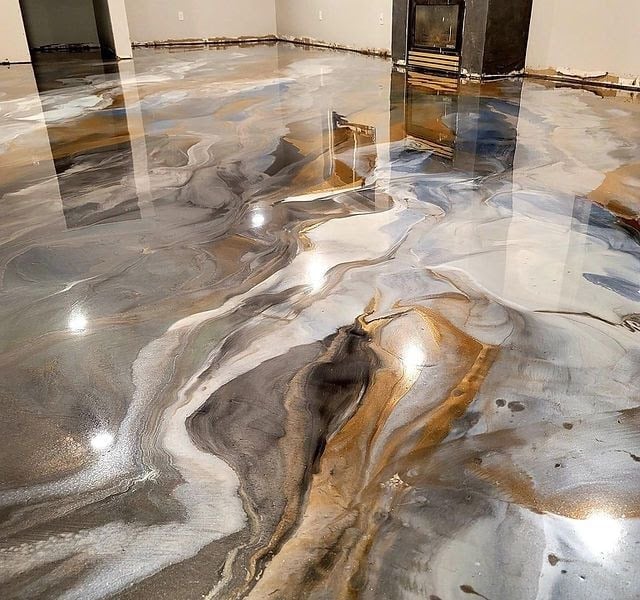 Polished concrete floor with decorative liquid metallic poured finish in swirling patterns of brown, gold, and grey tones in an empty gallery space